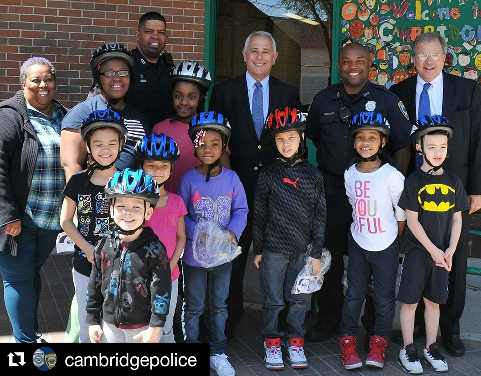 Attorney Ronald Gluck and Attorney David White of Breakstone, White & Gluck with Cambridge police officers and children who received bicycle helmets donated by the Boston personal injury law firm.