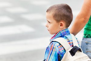 Boy at a crosswalk, holding a grown-ups' hand