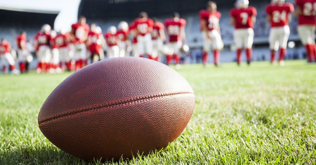 Football on a field and football players in background