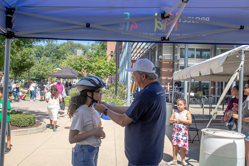 Attorney David W. White fits a bicycle helmet for a young girl at the Tierney Learning Center in South Boston.