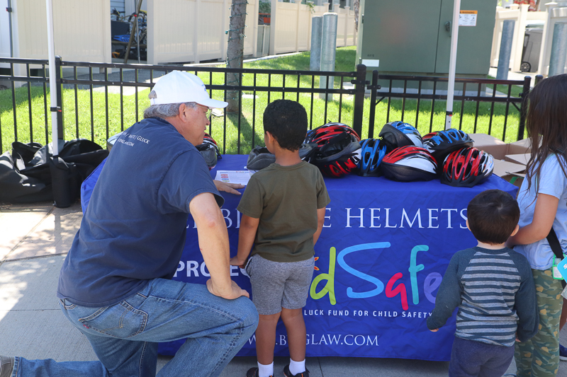 Attorney David W. White helping a young cyclist select a bicycle helmet.