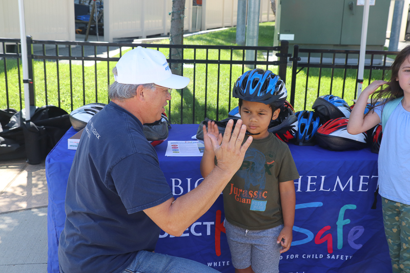 High five after Attorney David W. White fits a helmet for a young cyclist. Breakstone, White & Gluck donated the bicycle helmets to the Tierney Learning Center's Back to School BBQ.
