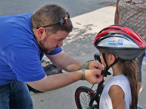 Man fitting Project KidSafe bicycle helmet for young girl in Lawrence, Massachusetts