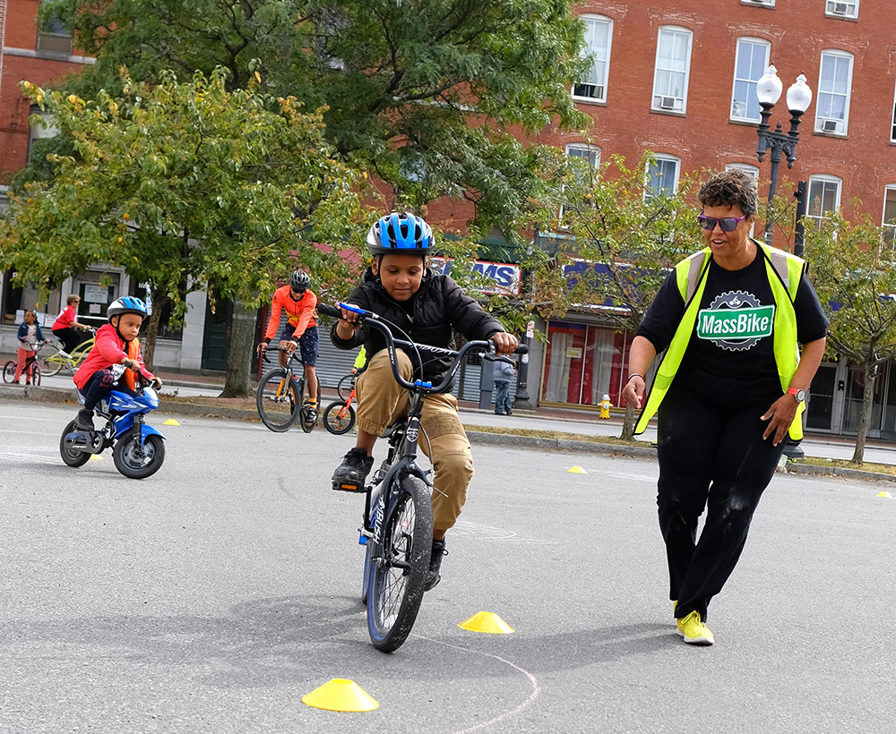 Child riding around obstacle course at the Lawrence Ciclovia. Breakstone, White & Gluck, a Boston personal injury law firm, donated bicycle helmets for the kids.