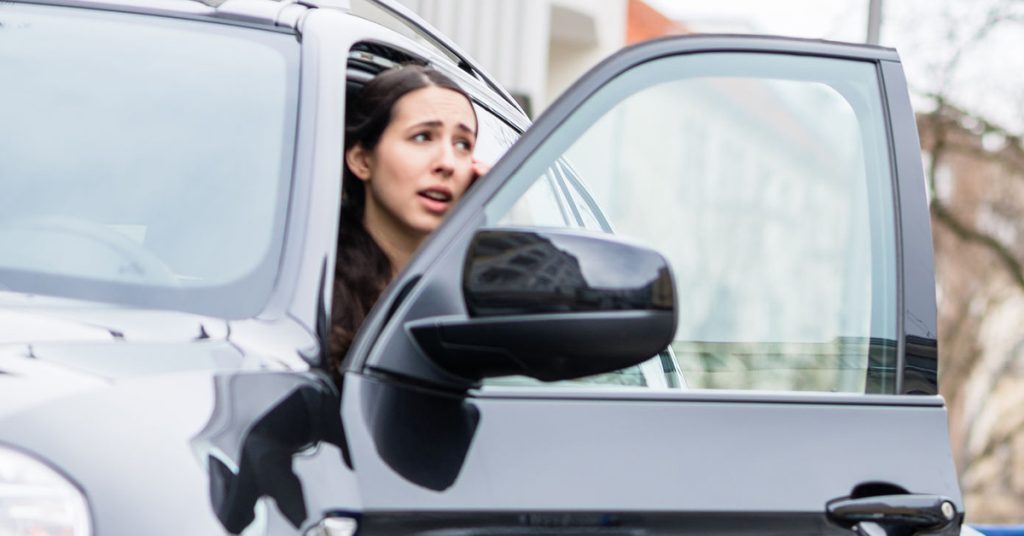 Woman with SUV door open, putting cyclists at risk for dooring injuries.