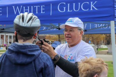 Attorney David W. White fitting helmets at Framingham Earth Day 2019. Part of Breakstone, White & Gluck's Project KidSafe campaign to prevent head injuries.