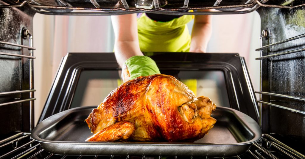 Woman putting Thanksgiving turkey in oven