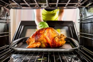 Woman putting Thanksgiving turkey in oven