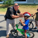 Everett Police officer fitting a free helmet for a young child. Helmet donated by Breakstone, White & Gluck's Project KidSafe campaign.