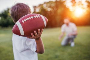 Boston child throwing football to father in the backyard.