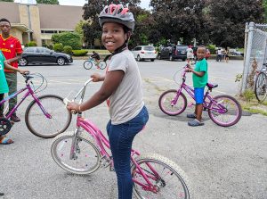Young child receives a free bike from The Bike Connector in Lowell and a free Project KidSafe bike helmet from Breakstone, White & Gluck, a Boston law firm.