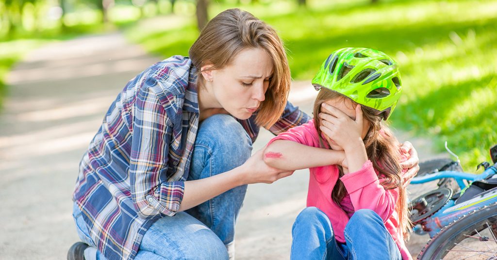 Mother looks at child's elbow after a bicycle fall