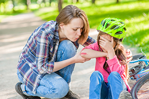 Mother helps daughter after a minor fall off a bicycle.