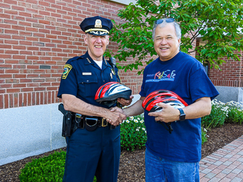 Norwood Police Chief receives children's bicycle helmets to help promote bike safety.