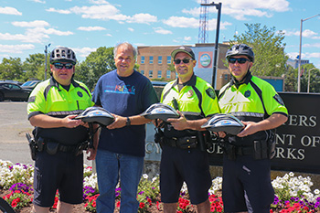 Quincy Police officers receive free bicycle helmets for children from Breakstone, White & Gluck of Boston.