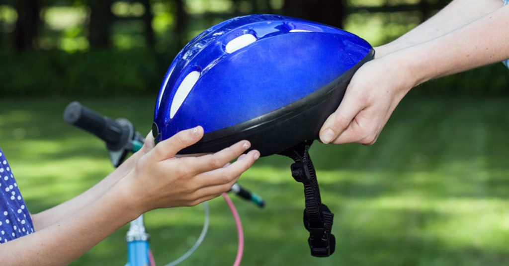 Parent giving child a bicycle helmet