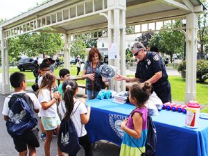 Waltham Police officer gives away free children's bicycle helmets donated by Boston law firm of Breakstone, White & Gluck