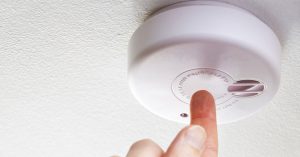 Homeowner testing smoke alarm