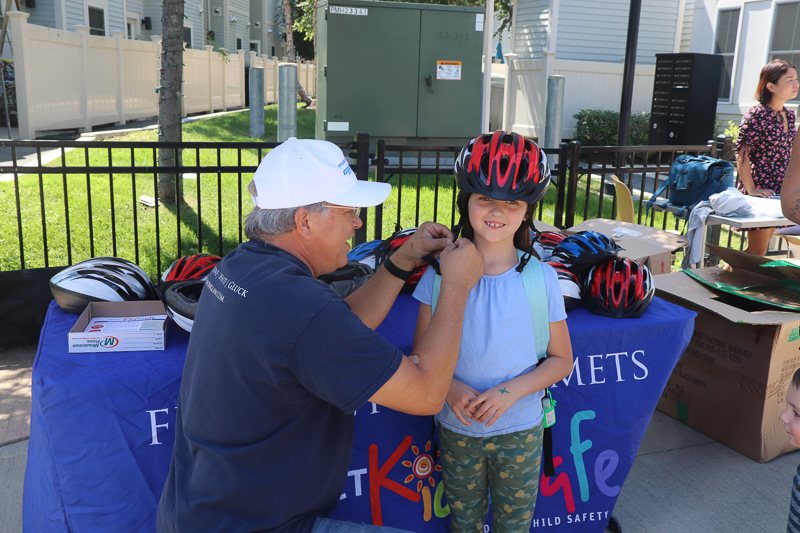 Attorney David W. White fits a bicycle helmet for a young girl at the Tierney Learning Center in South Boston.