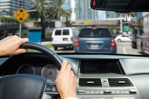 Driver hands on the wheel at intersection with traffic