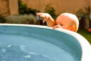 Baby reaching into pool